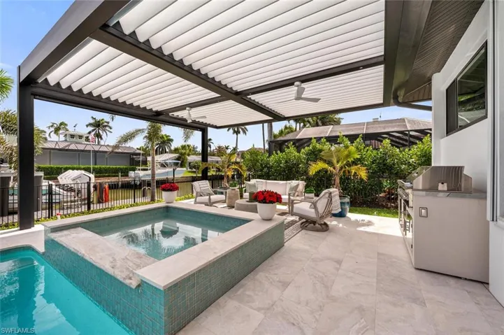 View of pool featuring a patio, fence, an in ground hot tub, exterior kitchen, and an outdoor living space