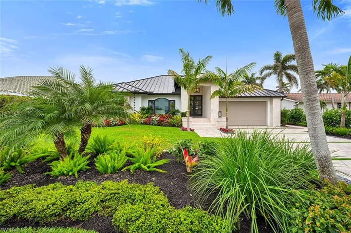 View of front of property with a standing seam roof, metal roof, an attached garage, and stucco siding