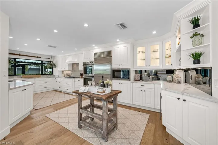Kitchen featuring light wood finished floors, visible vents, white cabinets, built in appliances, and open shelves
