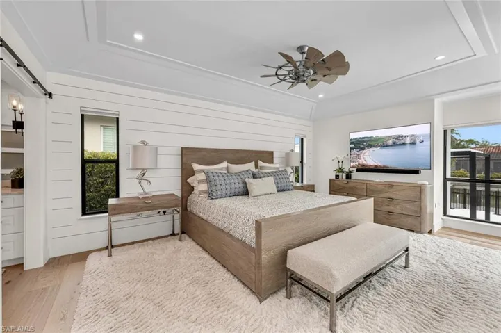 Bedroom featuring light wood-style floors, recessed lighting, multiple windows, and a barn door