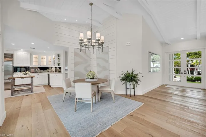 Dining space with light wood-style floors, beam ceiling, high vaulted ceiling, and a notable chandelier