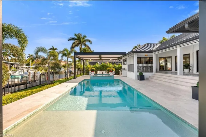 View of swimming pool with a patio, fence, and a pool with connected hot tub