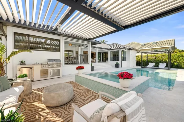 Pool with a patio area, a pergola, grilling area, and exterior kitchen