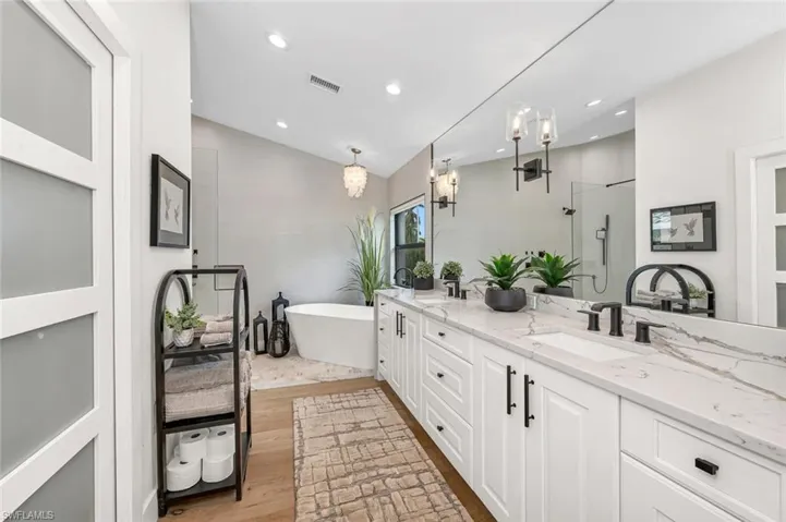 Bathroom featuring a sink, visible vents, vaulted ceiling, double vanity, and a stall shower