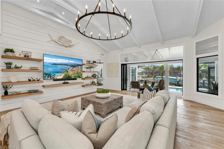 Living area with light wood finished floors, wooden walls, high vaulted ceiling, and beam ceiling