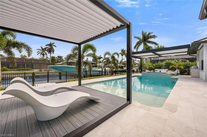 View of swimming pool featuring a pool with connected hot tub, a patio area, and fence