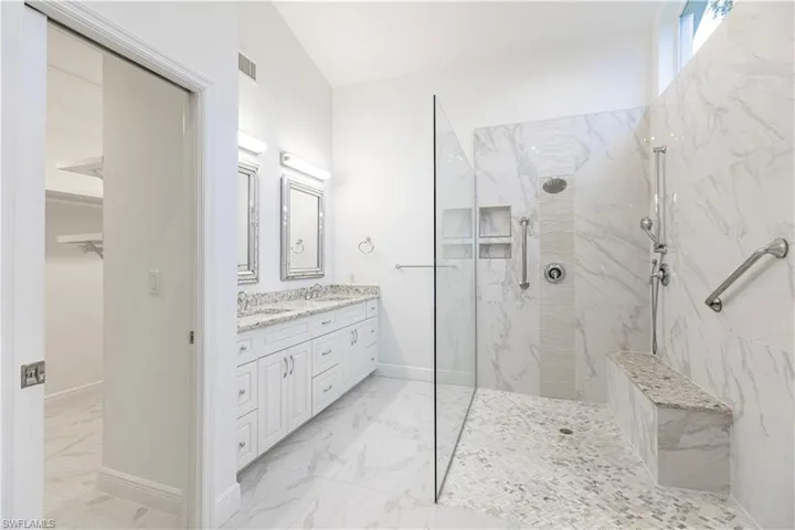 Bathroom with vaulted ceiling, a tile shower, and vanity