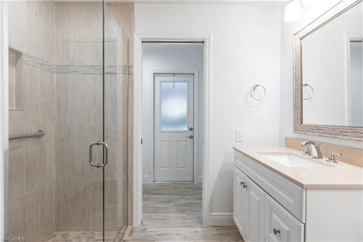 Bathroom with a shower with door, vanity, and wood-type flooring