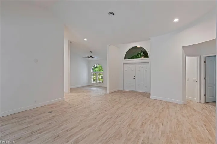 Unfurnished living room with vaulted ceiling, ceiling fan, and light hardwood / wood-style floors