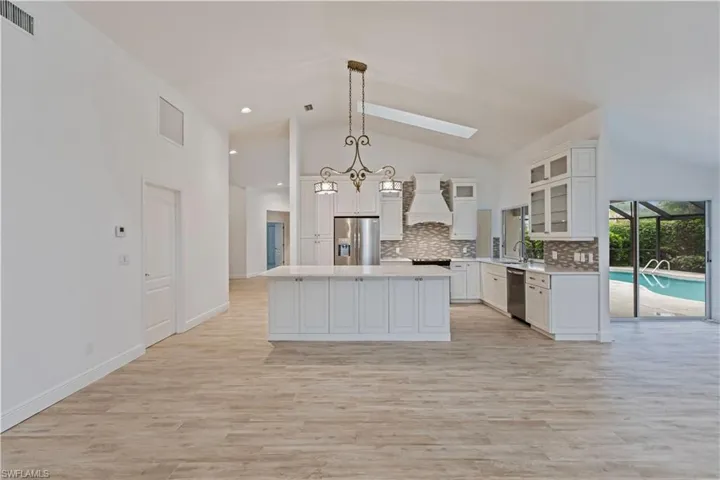 Kitchen featuring white cabinetry, stainless steel appliances, a center island, premium range hood, and hanging light fixtures