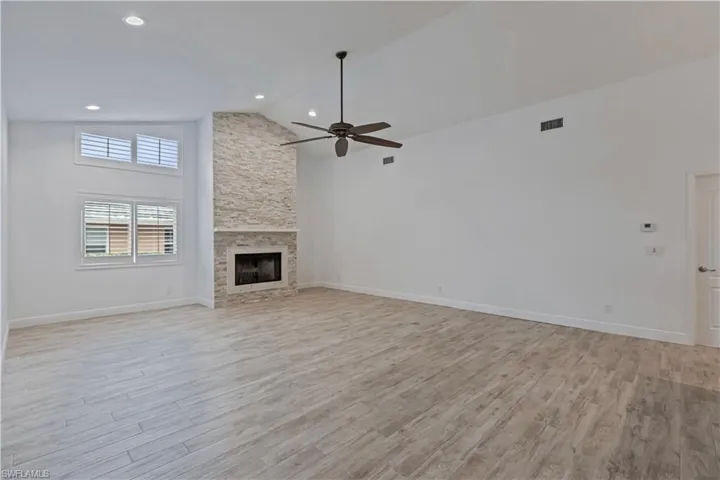 Unfurnished living room featuring a fireplace, high vaulted ceiling, ceiling fan, and light hardwood / wood-style floors