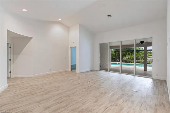 Unfurnished living room with light wood-type flooring, ceiling fan, and high vaulted ceiling