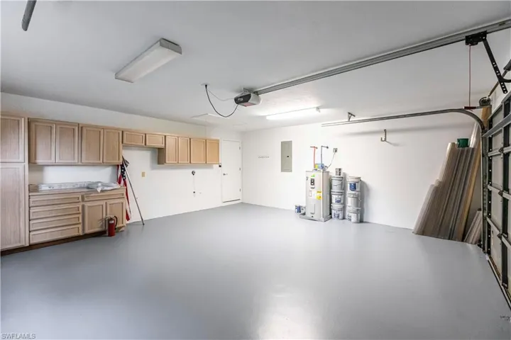 Garage with a garage door opener, water heater, and electric panel