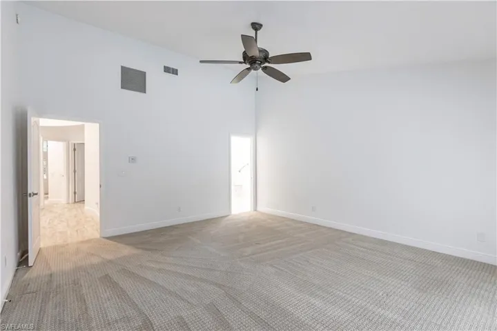 Spare room featuring a high ceiling, ceiling fan, and light colored carpet