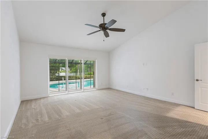 Carpeted empty room with vaulted ceiling and ceiling fan