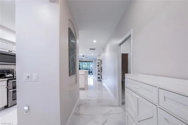 Corridor featuring arched walkways, recessed lighting, visible vents, baseboards, and marble finish floor