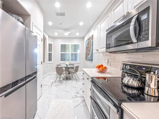 Kitchen featuring marble finish floor, visible vents, appliances with stainless steel finishes, and white cabinets