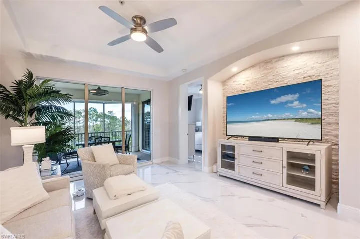 Living room with marble finish floor, a tray ceiling, a ceiling fan, and baseboards