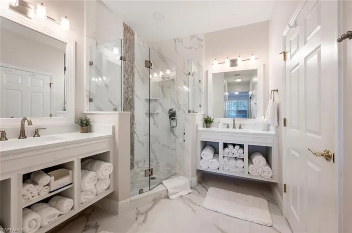 Full bathroom featuring marble finish floor, two vanities, a sink, and a marble finish shower