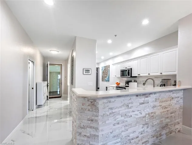 Kitchen featuring marble finish floor, stainless steel appliances, recessed lighting, decorative backsplash, and white cabinets
