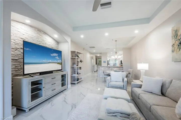 Living room with an inviting chandelier, a raised ceiling, visible vents, and recessed lighting