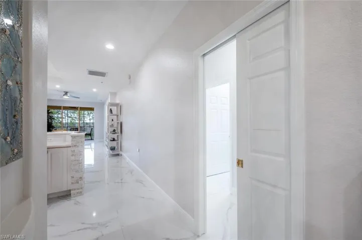 Corridor featuring arched walkways, recessed lighting, visible vents, baseboards, and marble finish floor