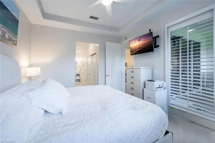 Bedroom featuring visible vents, a raised ceiling, connected bathroom, a ceiling fan, and a closet