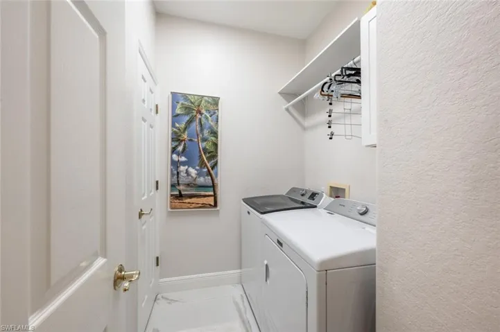 Washroom with laundry area, baseboards, marble finish floor, and washing machine and clothes dryer