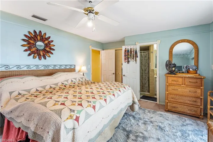 Bedroom featuring ceiling fan, visible vents, a closet, carpet, and ensuite bath