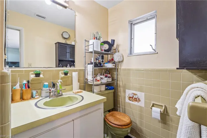 Bathroom featuring visible vents, wainscoting, vanity, and tile walls