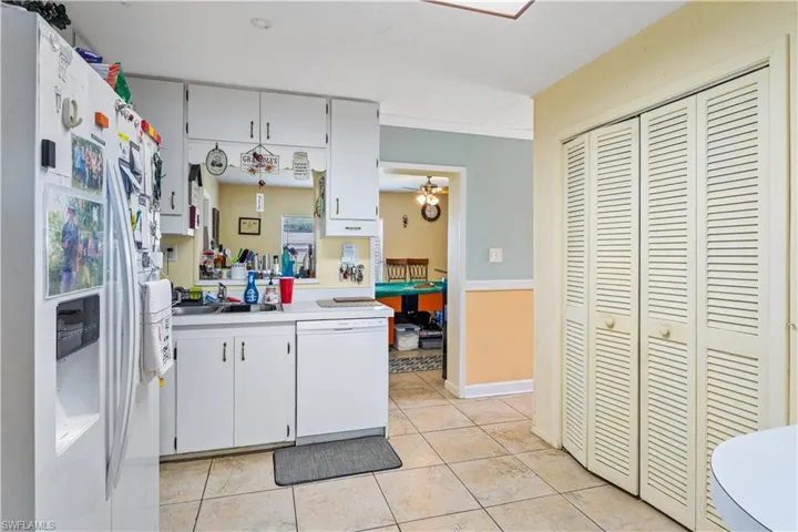Kitchen featuring white cabinets, a sink, white appliances, light countertops, and light tile patterned floors