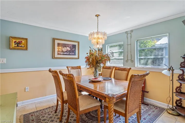Dining room featuring crown molding, baseboards, light tile patterned floors, and a notable chandelier