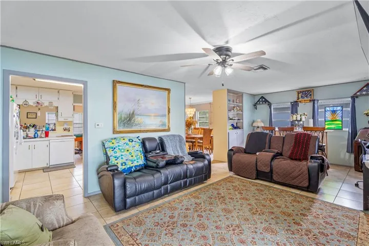 Living area featuring light tile patterned floors, a ceiling fan, and visible vents