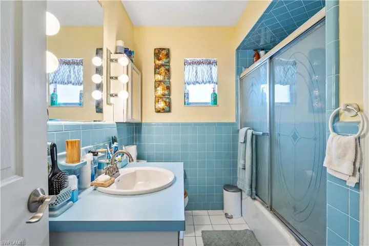 Full bath featuring a healthy amount of sunlight, tile walls, tile patterned flooring, and vanity