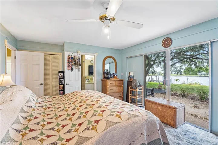 Bedroom featuring a ceiling fan, connected bathroom, a water view, and access to exterior