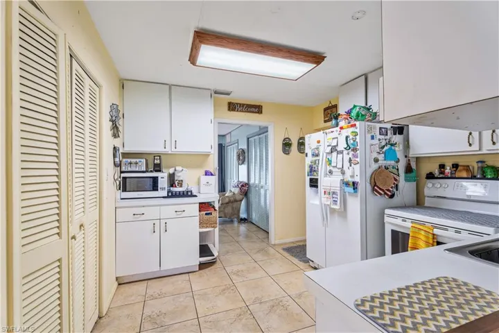 Kitchen featuring white appliances, white cabinets, light tile patterned floors, and light countertops
