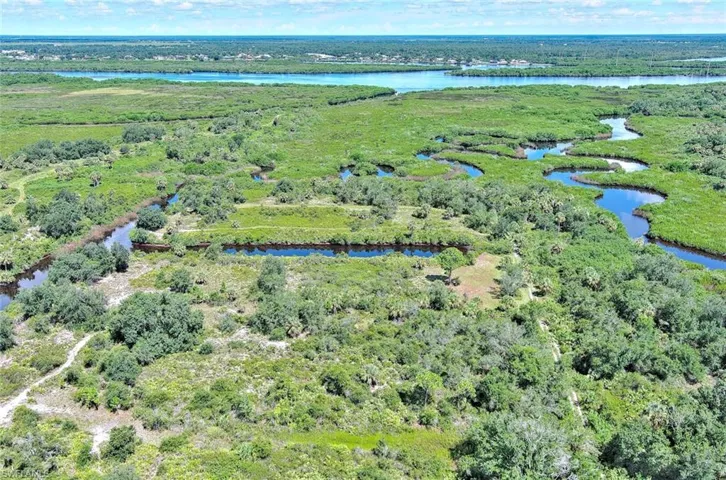View of property location with a heavily wooded area and a nearby body of water