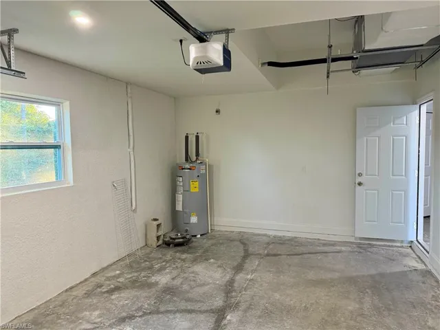 Garage featuring a garage door opener and electric water heater