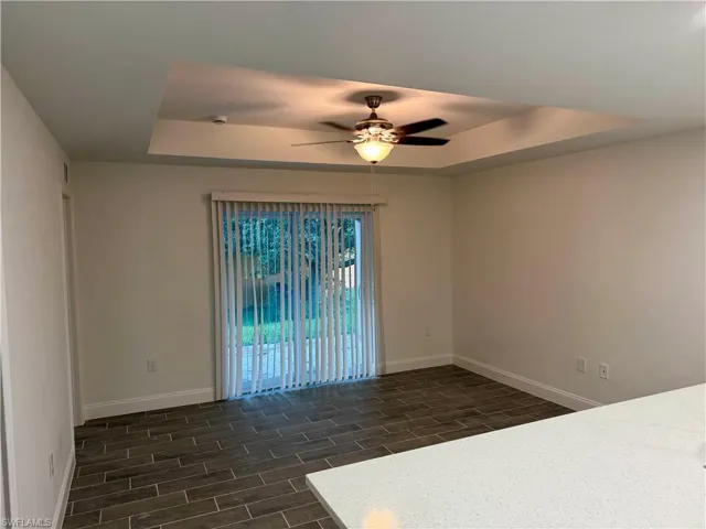 Spare room with a raised ceiling, wood tiled floors, and ceiling fan
