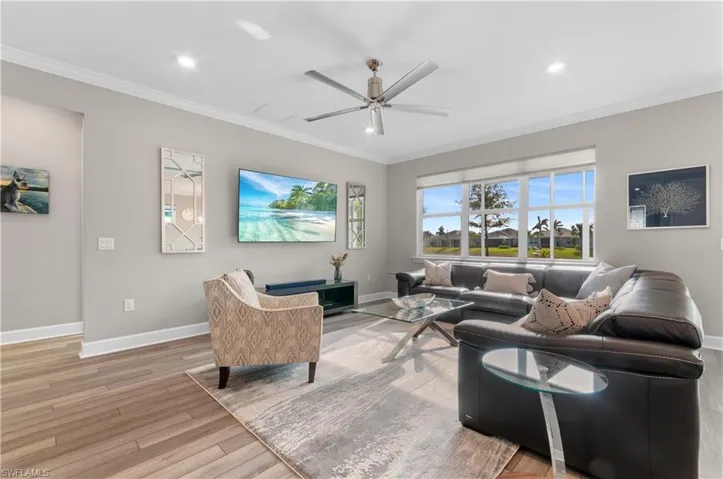 Living room featuring ceiling fan, wood-type flooring, and ornamental molding
