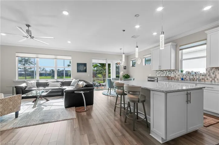 Kitchen with decorative light fixtures, a kitchen island, light stone countertops, and white cabinetry