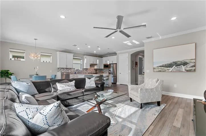 Living room featuring ceiling fan with notable chandelier, light hardwood / wood-style flooring, and ornamental molding