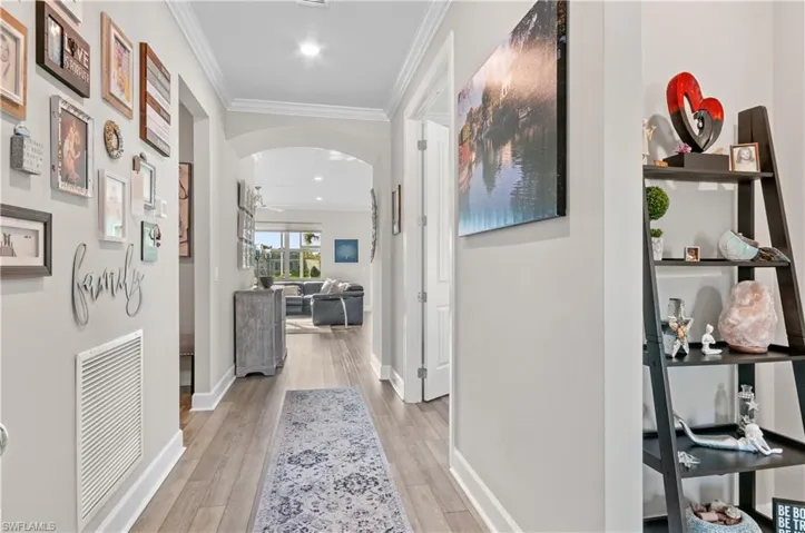 Hallway with light hardwood / wood-style floors and ornamental molding