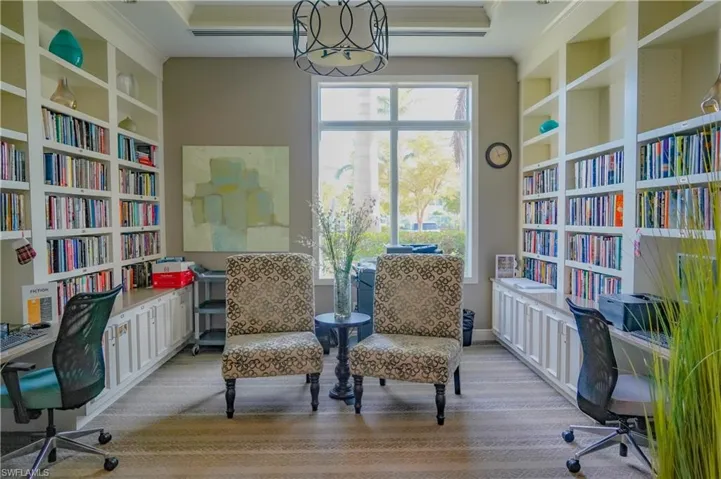 Sitting room with built in shelves, crown molding, and light carpet