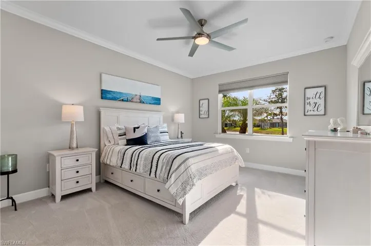 Carpeted bedroom featuring ceiling fan and crown molding