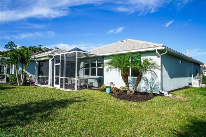 Back of house featuring a lawn and central air condition unit