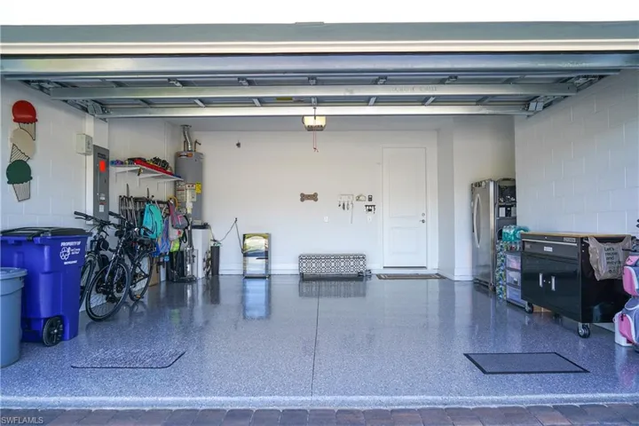 Garage with stainless steel fridge, gas water heater, and electric panel