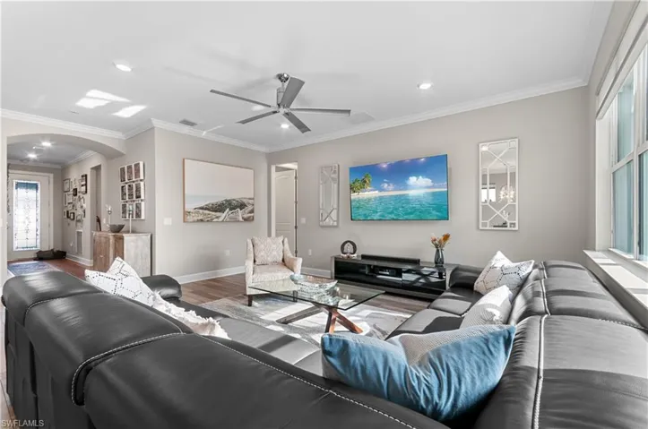 Living room with ceiling fan, wood-type flooring, and ornamental molding