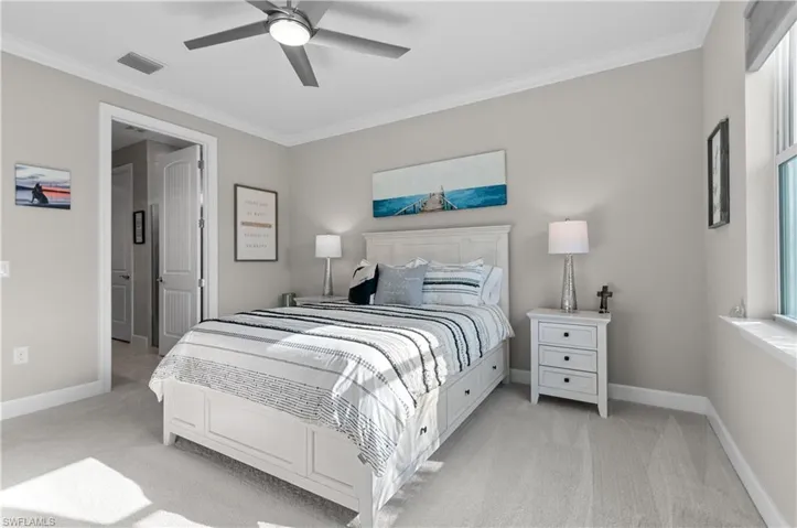 Bedroom with ceiling fan, crown molding, and light colored carpet