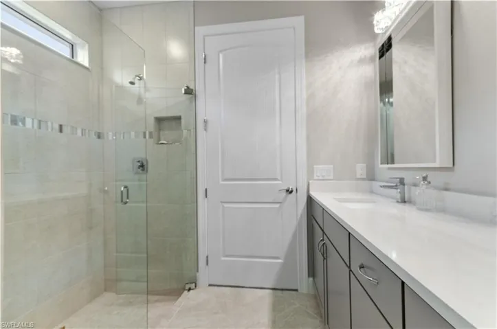 Bathroom featuring tile patterned flooring, vanity, and walk in shower